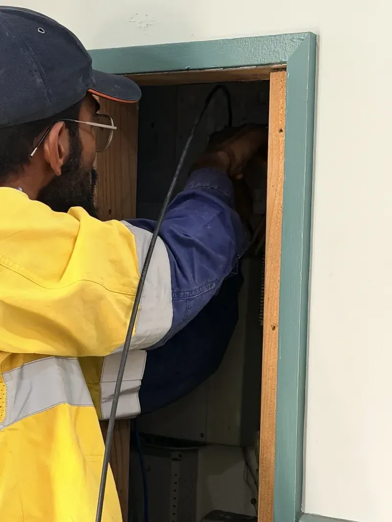 Netlink cabler pulling a new Cat6 lead cable through a wall cavity into an NBN wiring box during a Hunter region service install