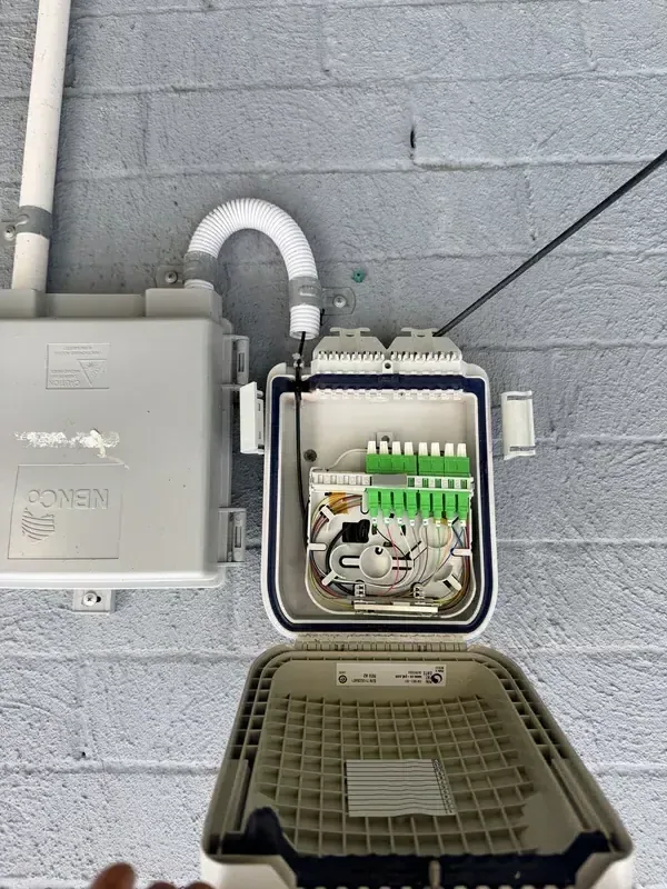 Netlink fibre-optic distribution enclosure with green SC/APC connectors mounted alongside an NBNCo NCD box on a Hunter Valley commercial premises — NBN fibre splicing and termination