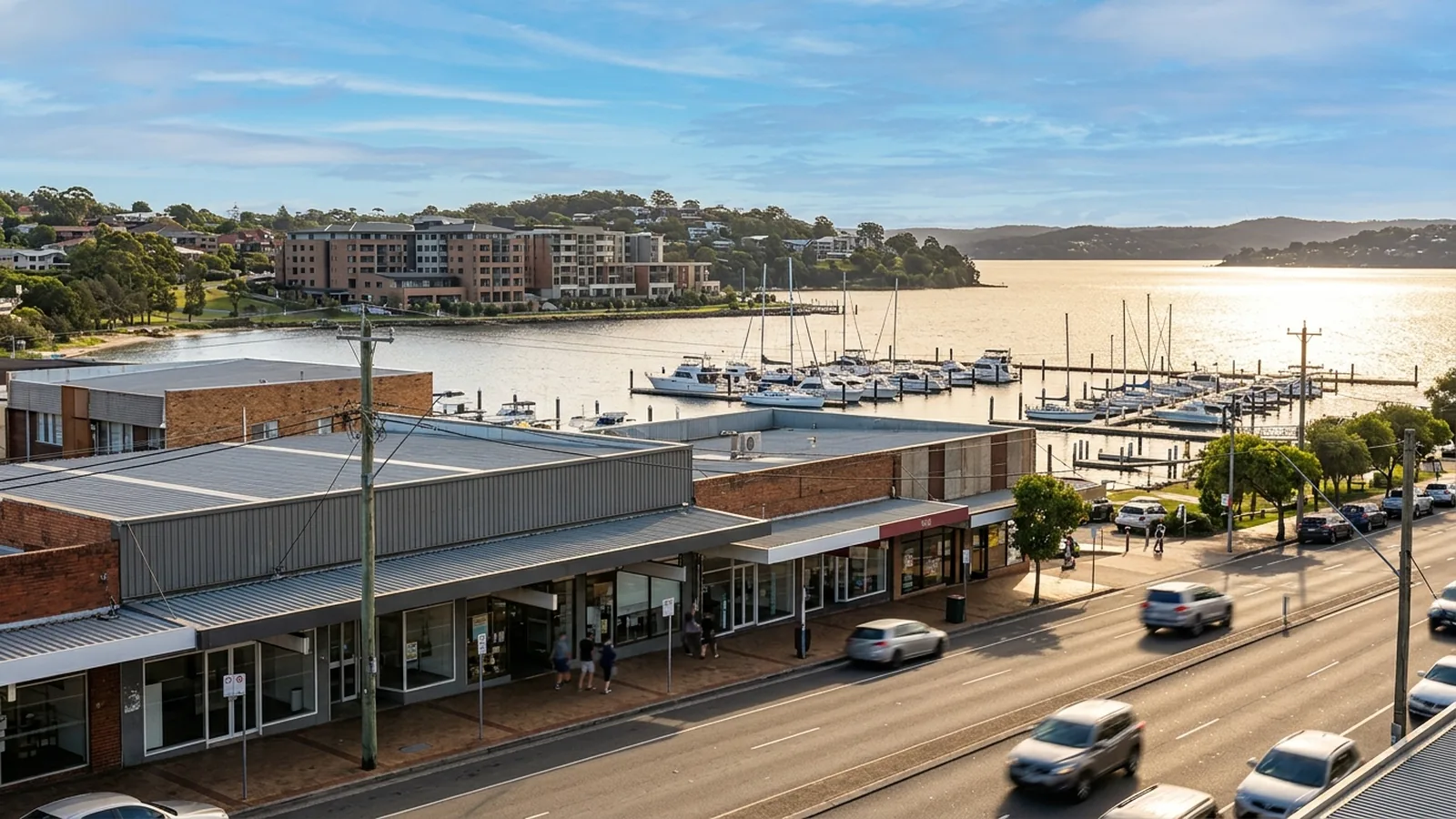 Belmont Pacific Highway retail frontage with the Belmont marina and moored yachts visible beyond — Netlink highway-frontage and marina CCTV service area