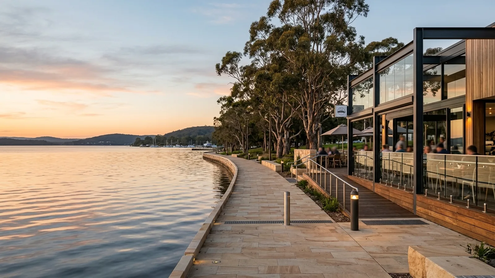 Warners Bay lakefront Esplanade at golden hour — lakeside cafe with alfresco decking and shared foreshore path — Netlink lakefront hospitality WDR CCTV service area